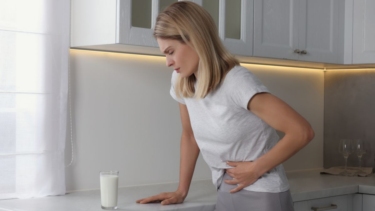 persona con dolor de barriga delante de vaso de leche